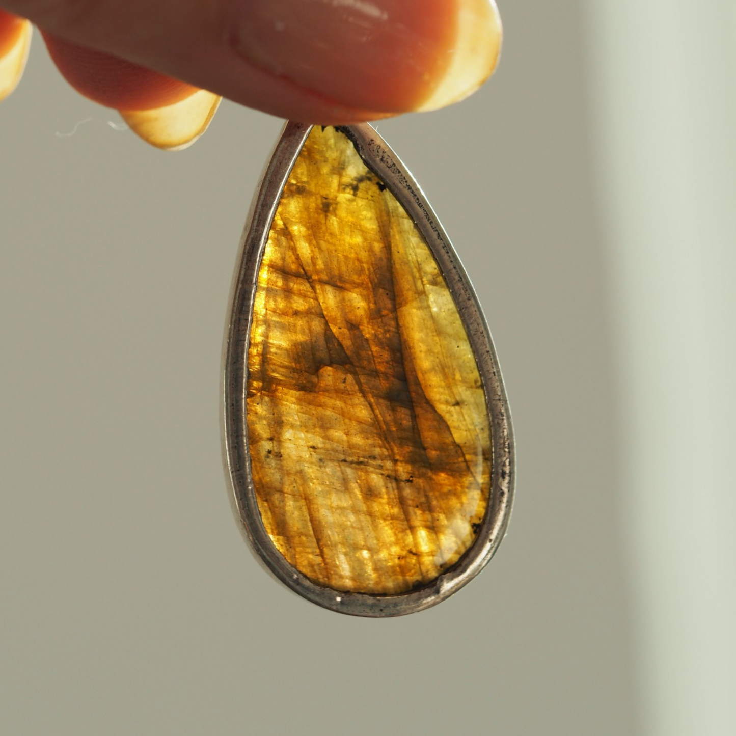 Backlit reverse of labradorite pendant showing golden tones