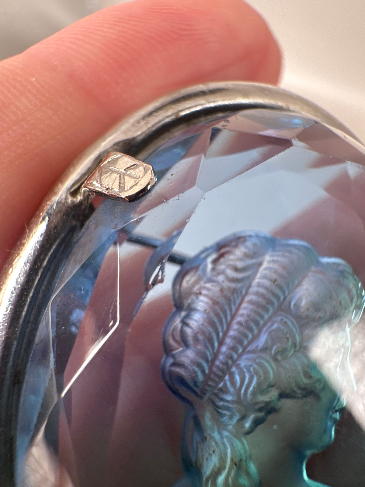 Close-up detail of one prong corner showing partially visible maker's mark (shield or geometric shape, text unreadable)
