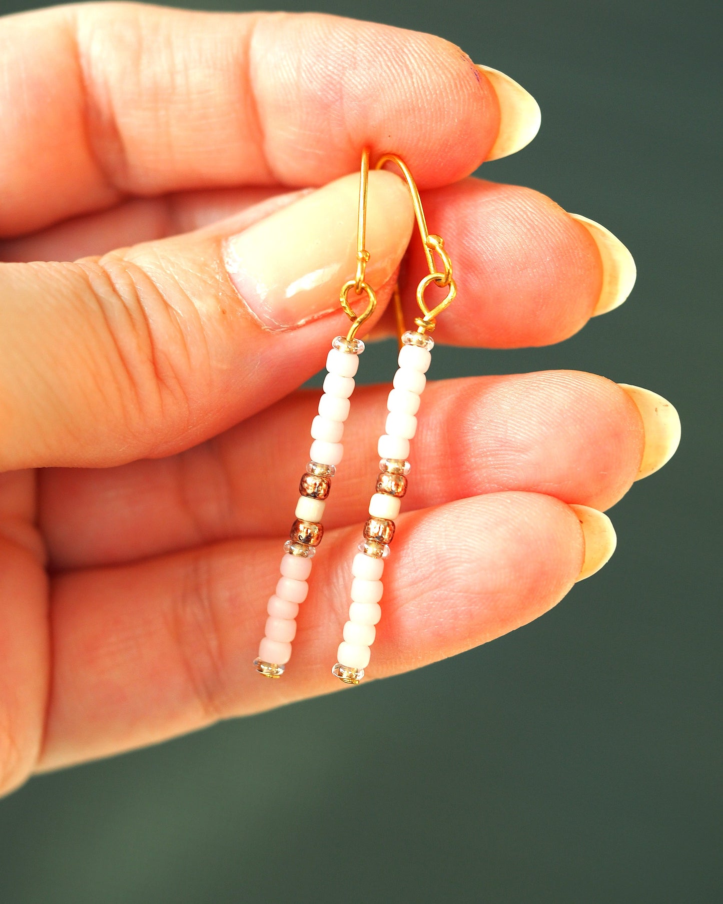 Pink beaded drop earrings held in hand for scale, showing 1.5 inch drop length with graduated glass beads and gold spacers