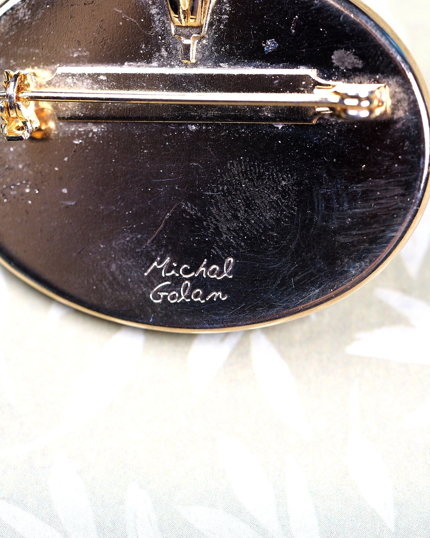 Close-up of engraved Michal Golan signature on black enamel reverse