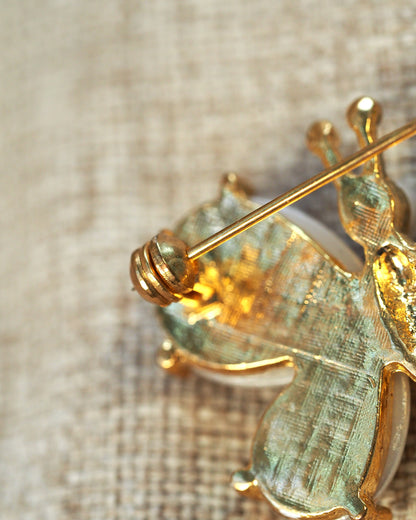 Close-up of brooch reverse showing pin mechanism and textured gold-tone finish, no visible wear