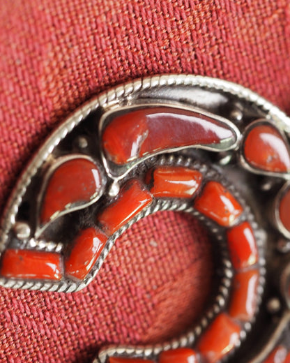 Close-up of red coral inlay in silver bezels, showing glossy cabochon surfaces and rope wire detail