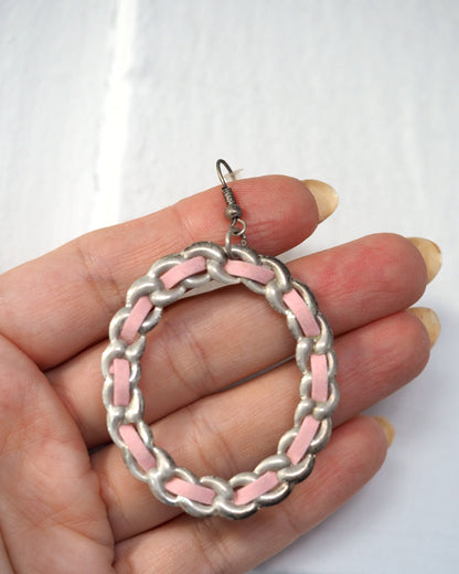 1970s pink enamel and silver-tone chainlink hoop earring held in hand, showing oval silhouette and interlocking links, front view