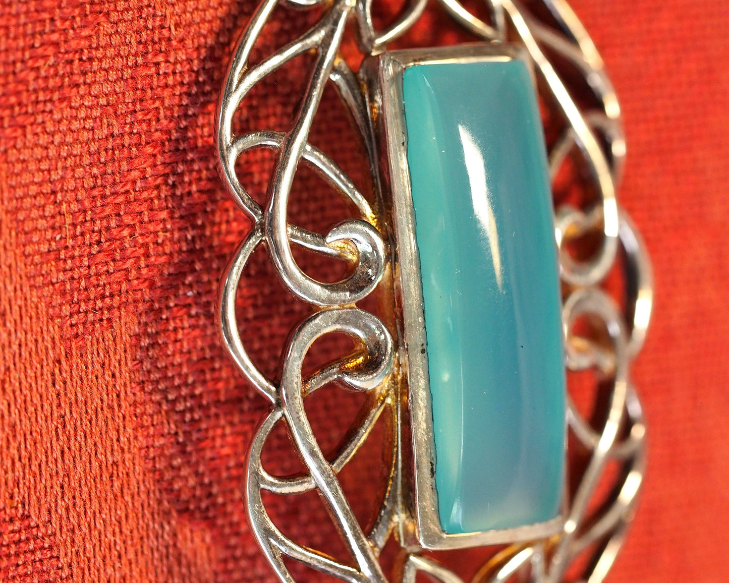 Side close-up showing bezel-set rectangular chalcedony cabochon and symmetrical scrollwork on Derewala pendant