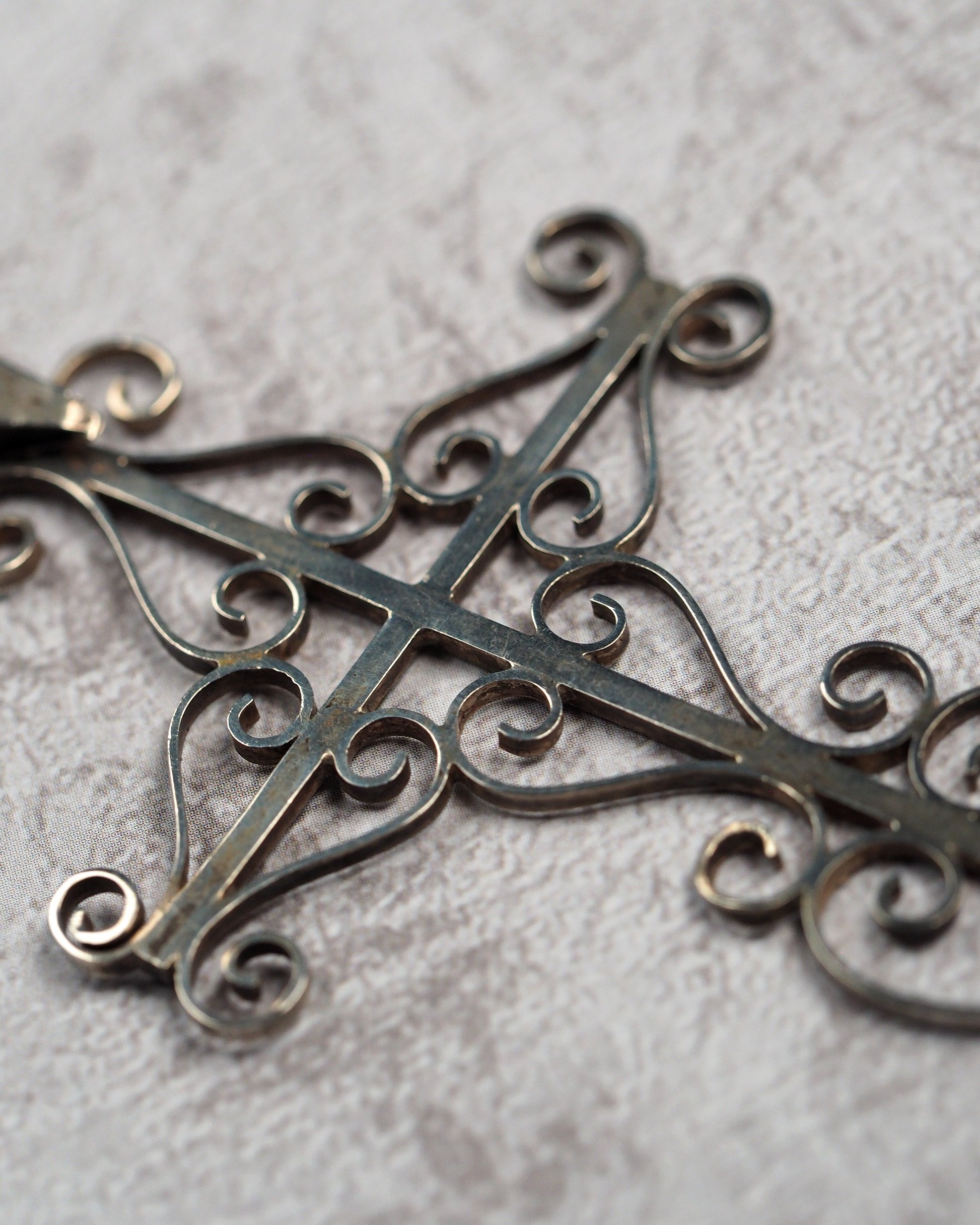 Detail of curled scrollwork and oxidized recesses on the Taxco silver cross