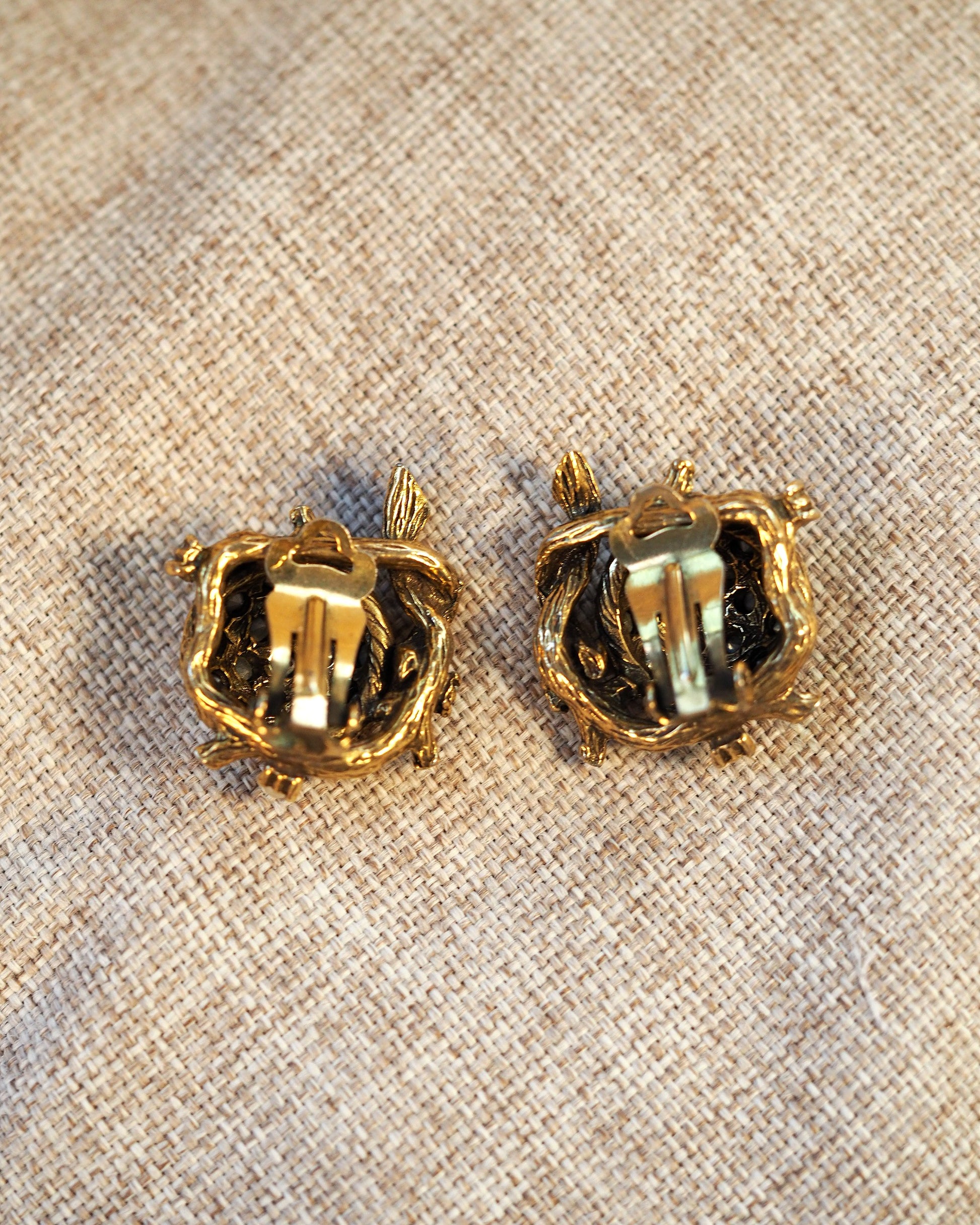 reverse view of both clip earrings showing clip-on backs and antique gold finish on metal