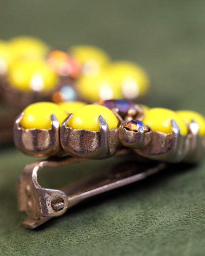 Side view showing pronged settings holding yellow glass cabochons and clip-on backs with screw adjustment