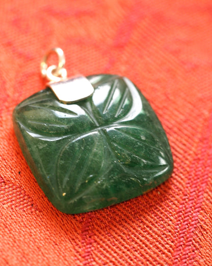 close-up of the carved aventurine stone showing the raised floral quadrant pattern and translucent green depth