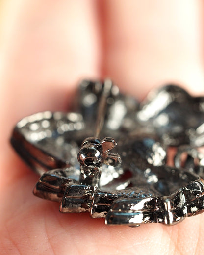 close-up of brooch reverse with pin mechanism in focus, teal rhinestones visible through hollow-back construction
