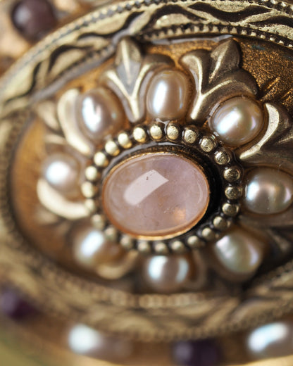 Close-up of rose-colored center cabochon in beaded bezel surrounded by pearl-like petals