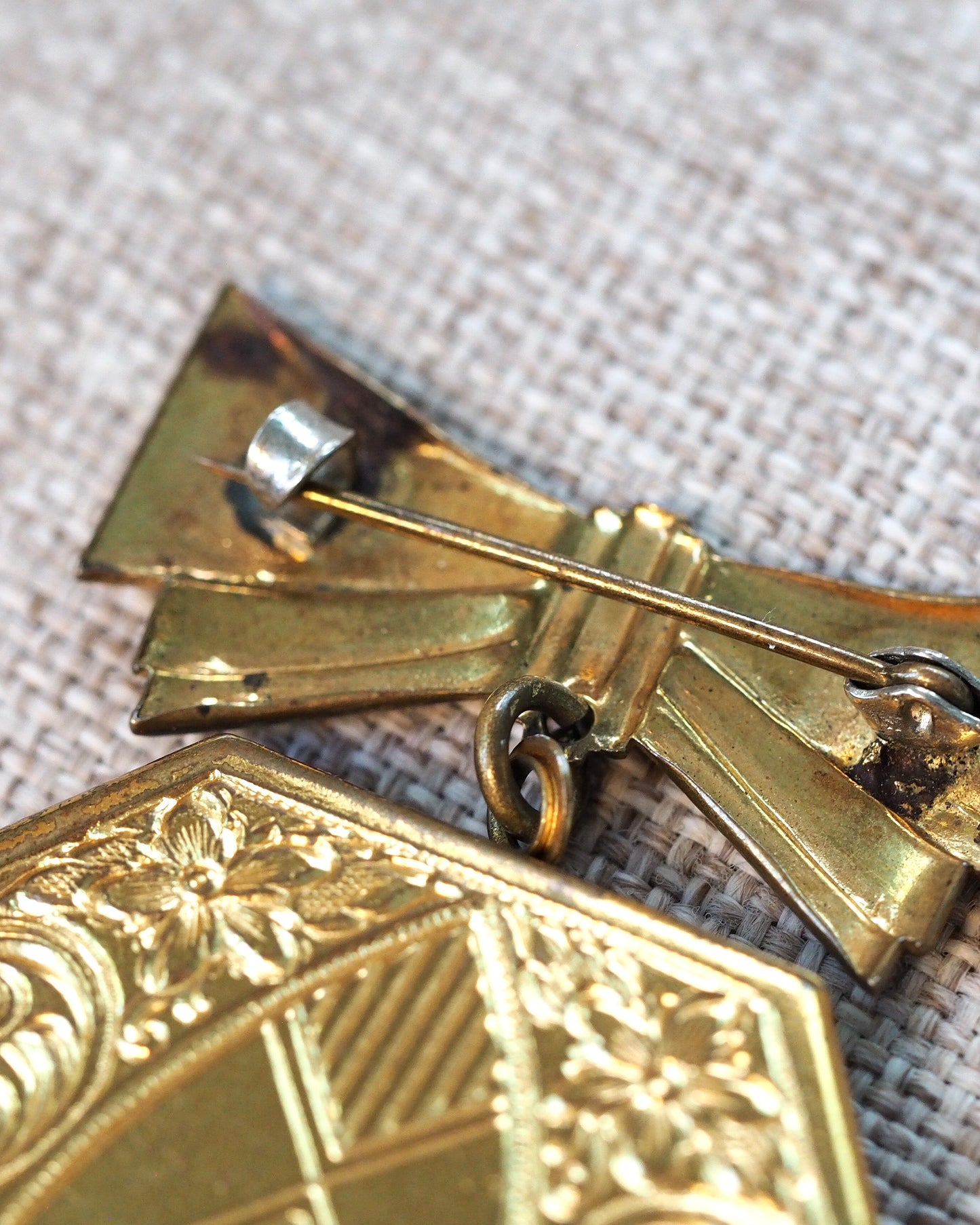 Detail of the bow accent and jump ring connection, showing pin clasp hardware on the reverse