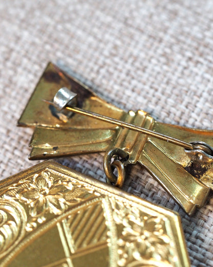 Detail of the bow accent and jump ring connection, showing pin clasp hardware on the reverse