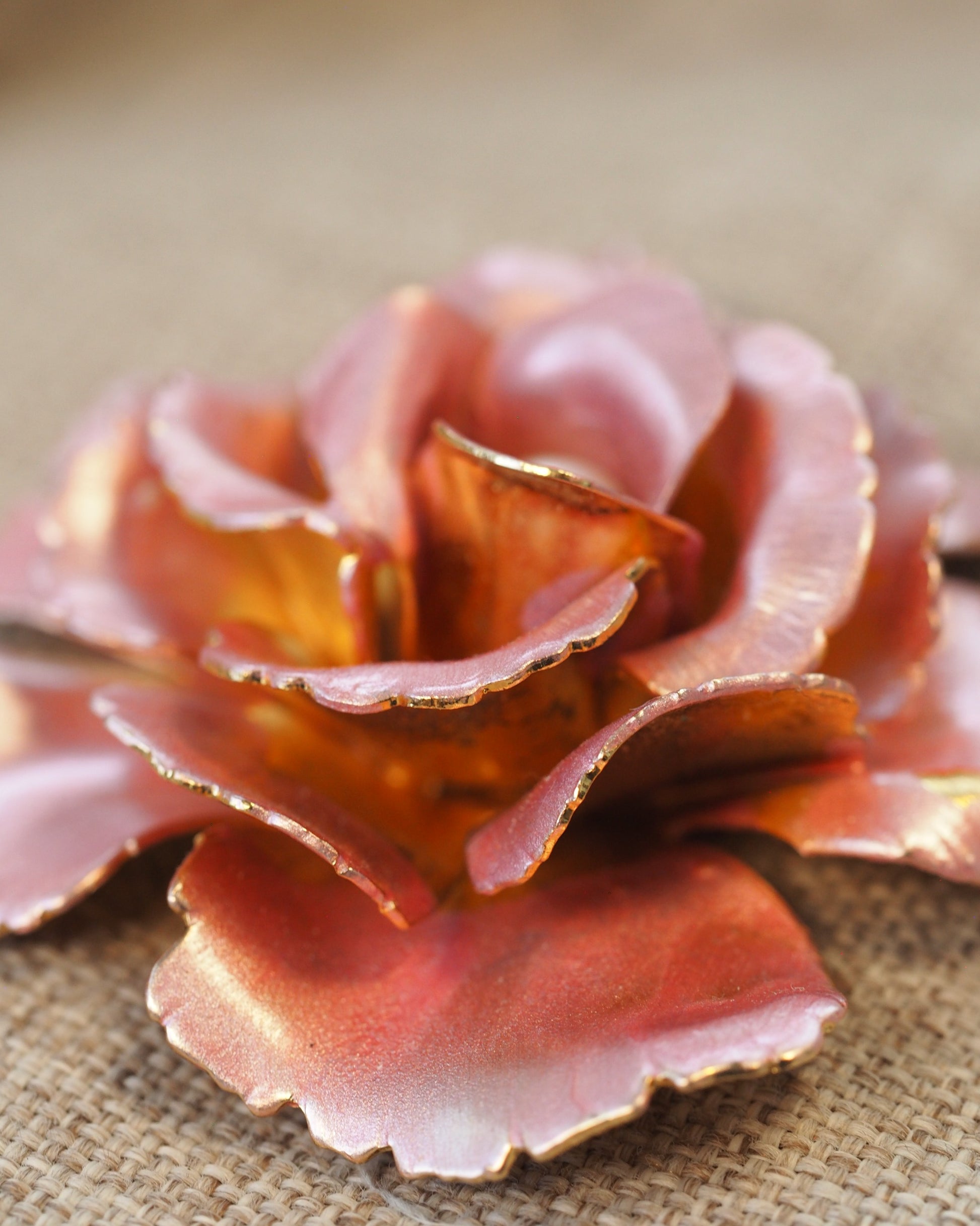 Close-up of pink enamel rose center with faux pearl and gold-edged scalloped petals