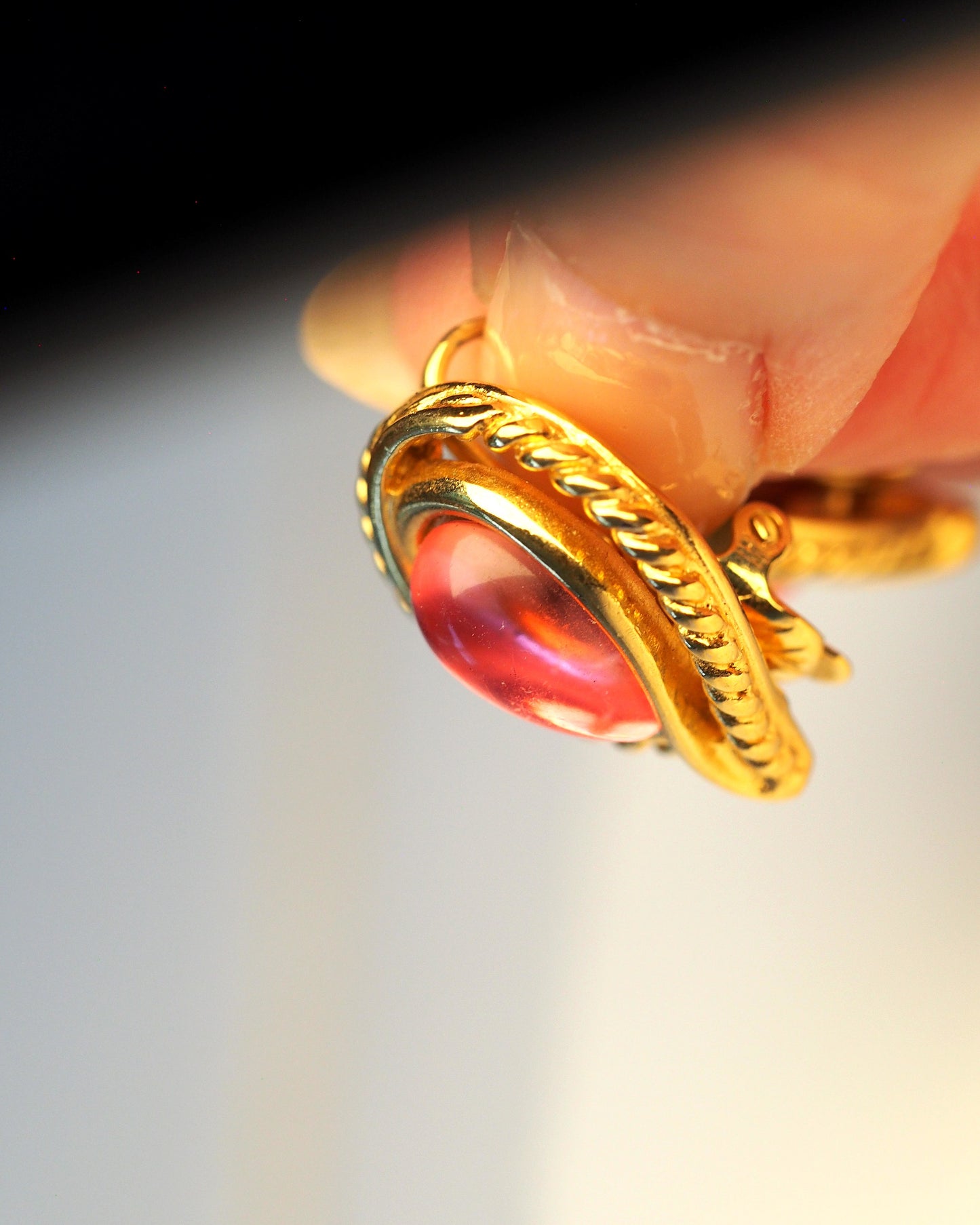 Single Trifari clip earring shown at angle on an earlobe, highlighting the teardrop shape and rope-twist border detail