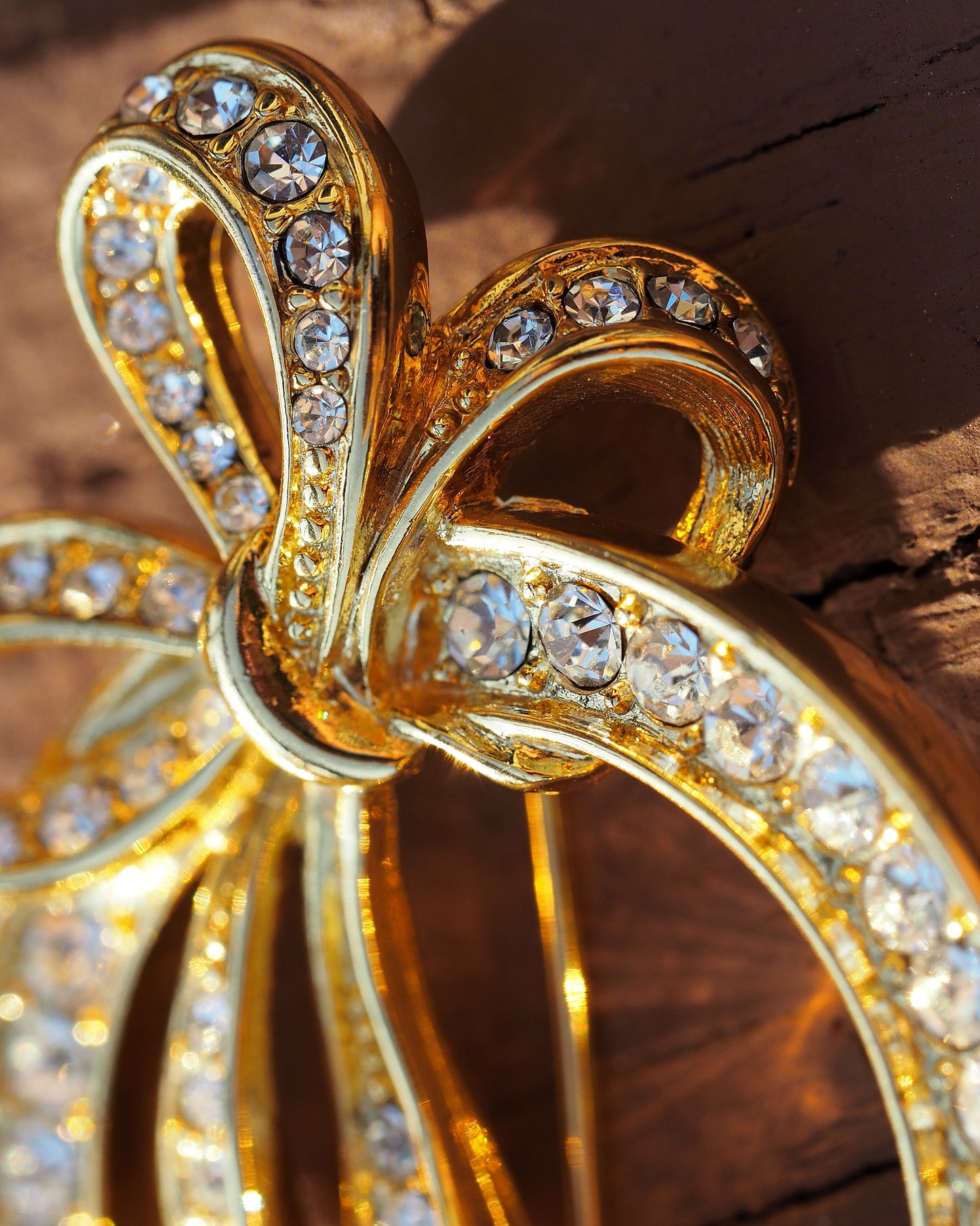 Detail of the raised bow knot where the ribbon loops cross, with rhinestones visible in the gold-tone setting