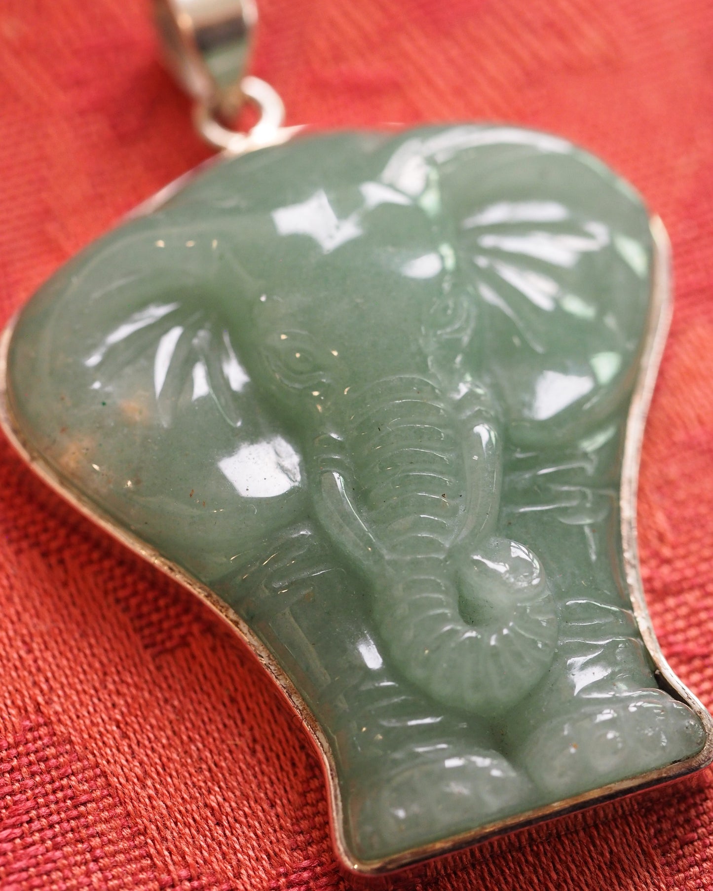 Close-up of the carved aventurine elephant pendant showing trunk segments, ear texture, and translucent green stone with natural inclusions