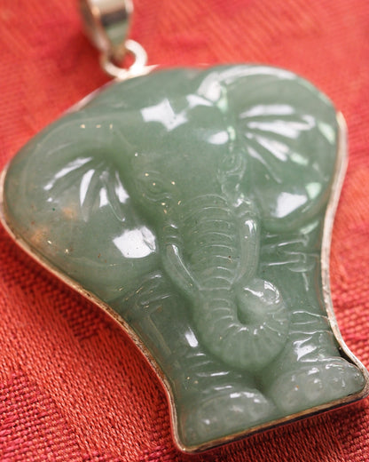 Close-up of the carved aventurine elephant pendant showing trunk segments, ear texture, and translucent green stone with natural inclusions