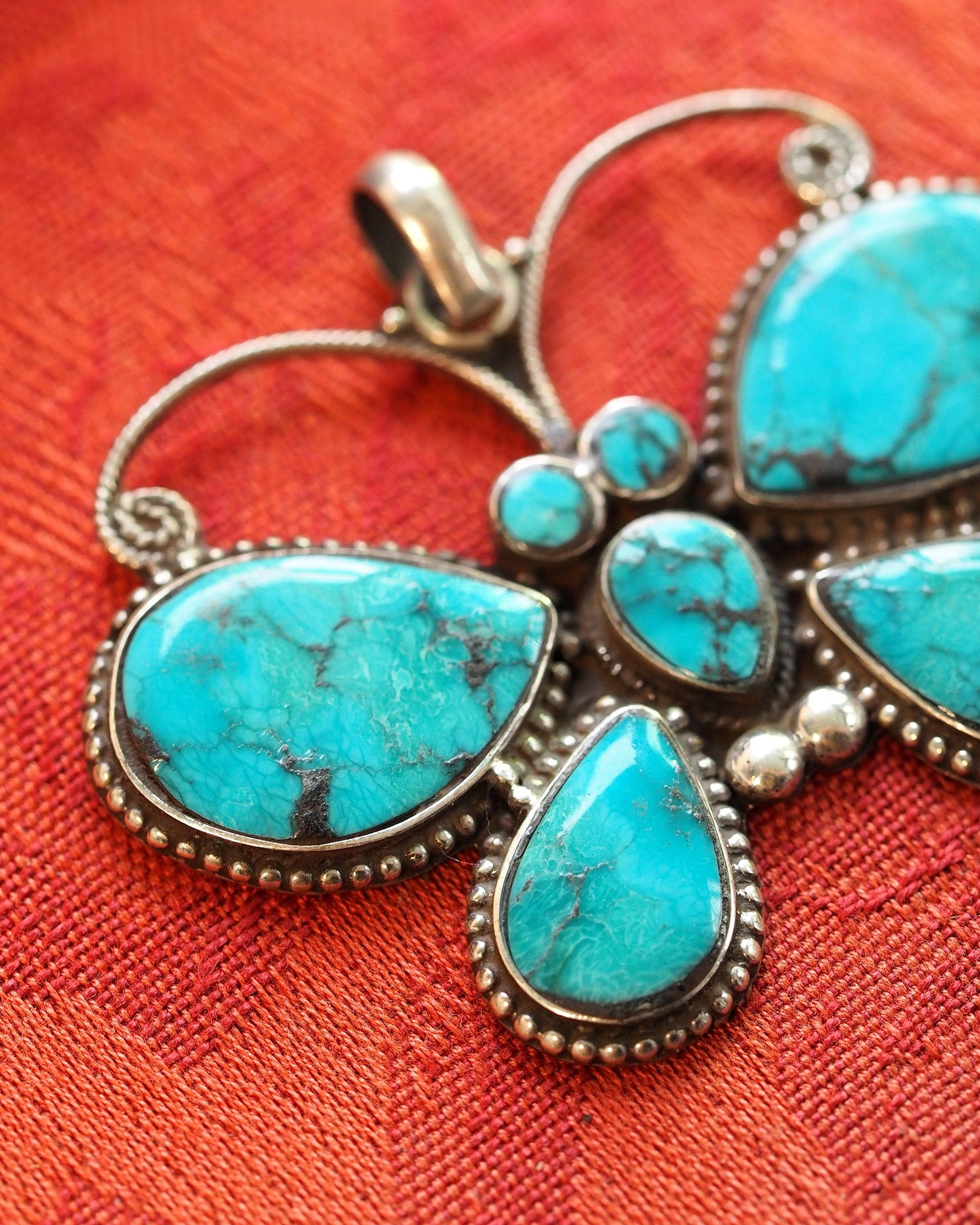 Close-up of turquoise cabochons with dark matrix pattern and beaded sterling silver borders