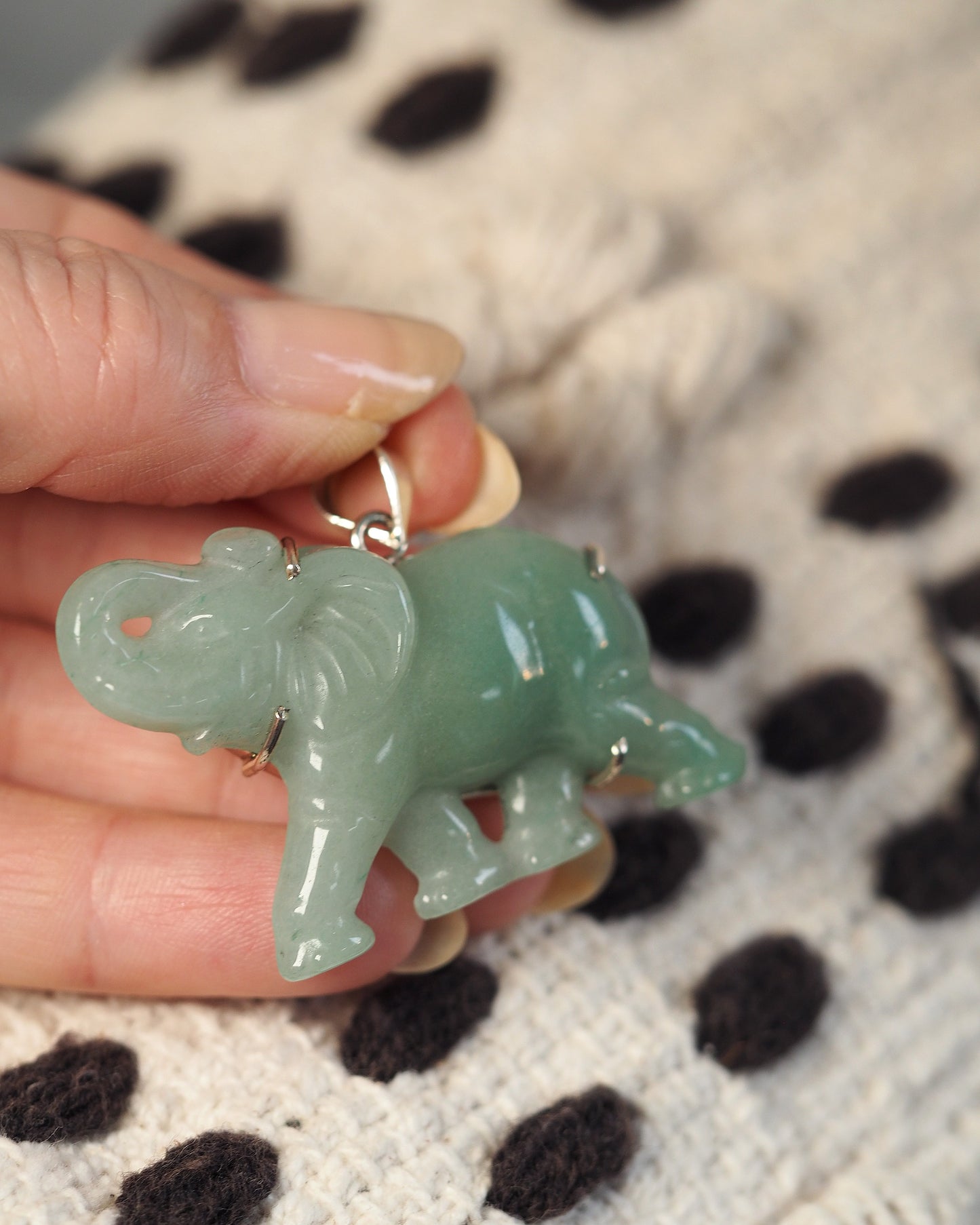 Aventurine elephant pendant held in hand for scale, showing two-inch length and translucent green stone quality