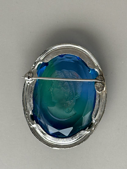 Reverse of blue glass cameo brooch showing open-back construction, C-clasp with safety catch, and engraved linear border detail