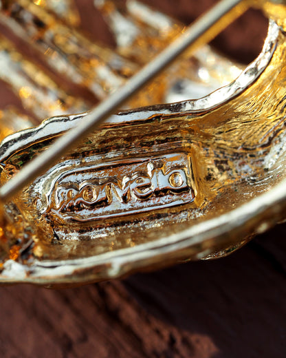 Close-up of Marvella signature stamp on reverse of swan brooch in rectangular cartouche