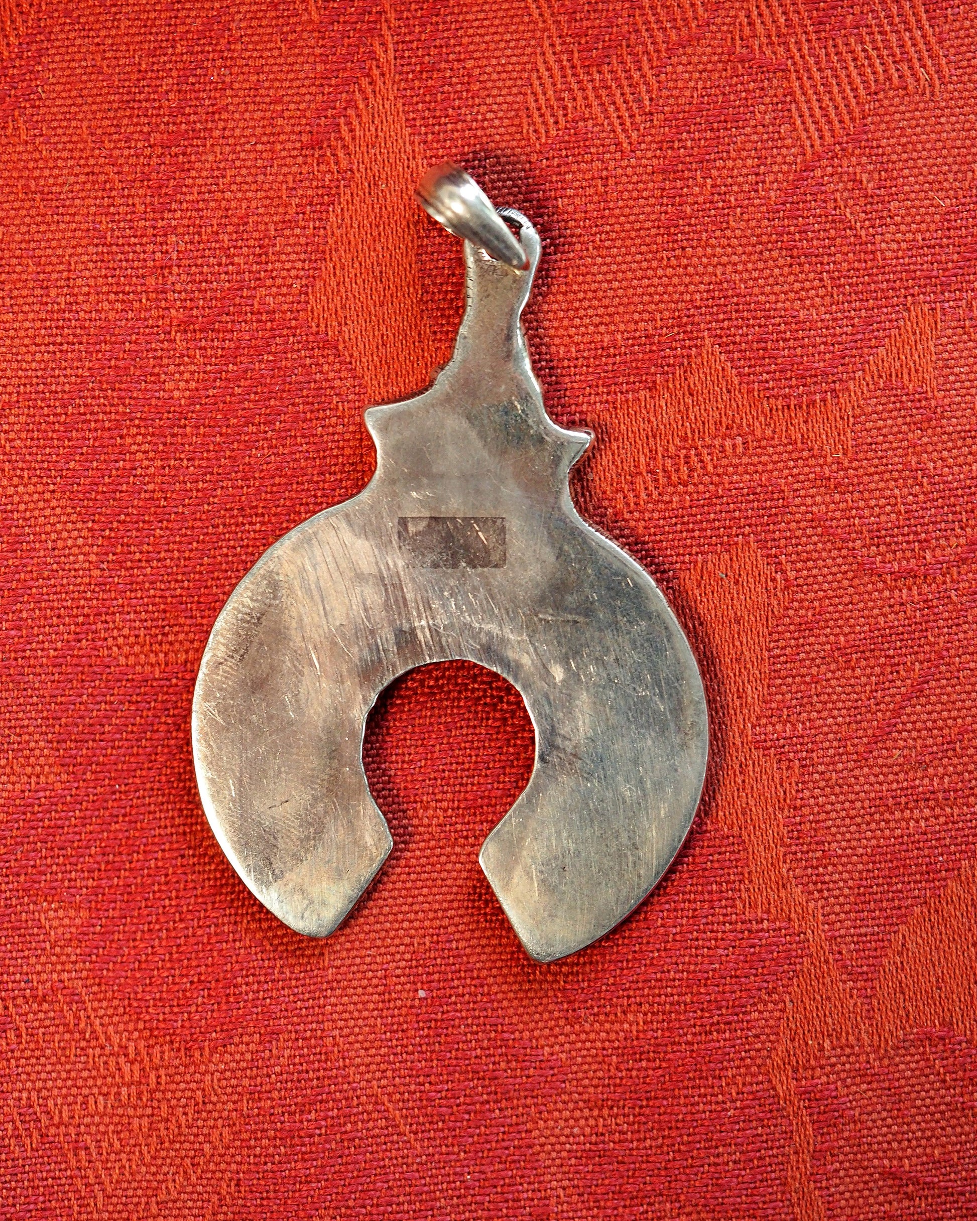 Reverse of silver naja pendant showing hand-fabricated construction, file marks, and slide bail