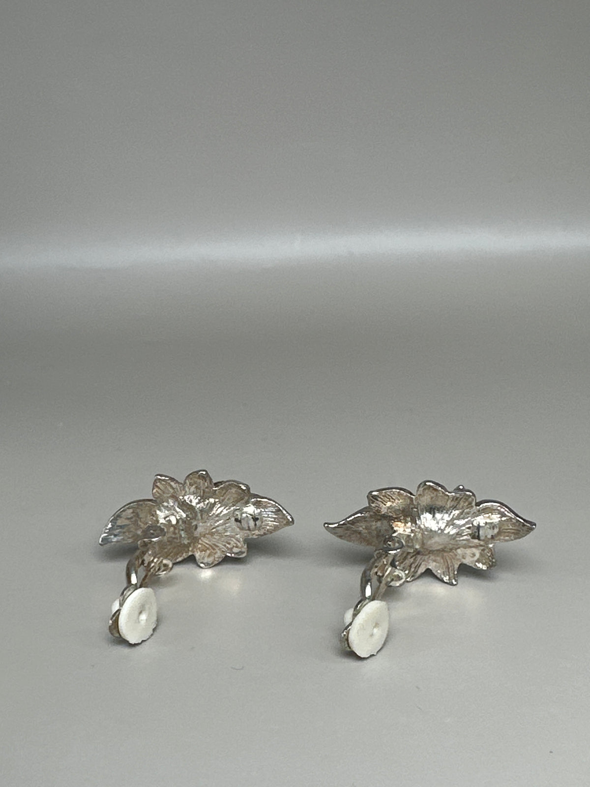 Clip earrings photographed flat showing backs with clip mechanisms and individual leaf assembly