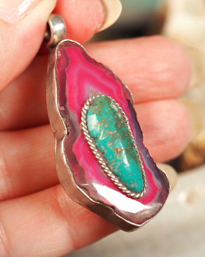 Dyed pink agate slice pendant held in hand for scale