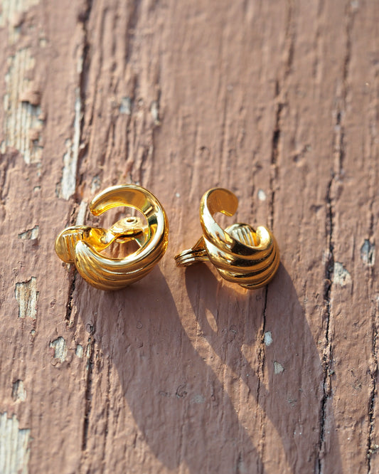 Monet gold-plated swoosh clip earrings, front view, three stacked curved bands in mirror-bright finish