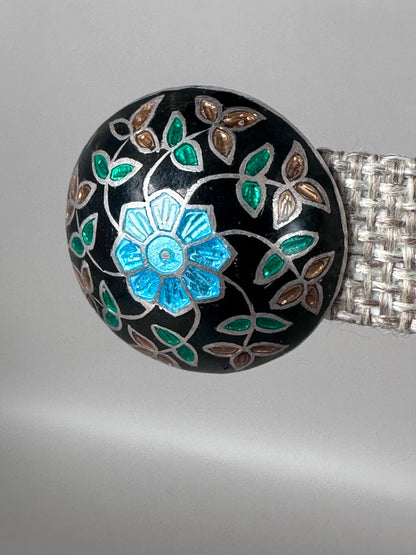 Close view of blue green and bronze floral enamel on black ground