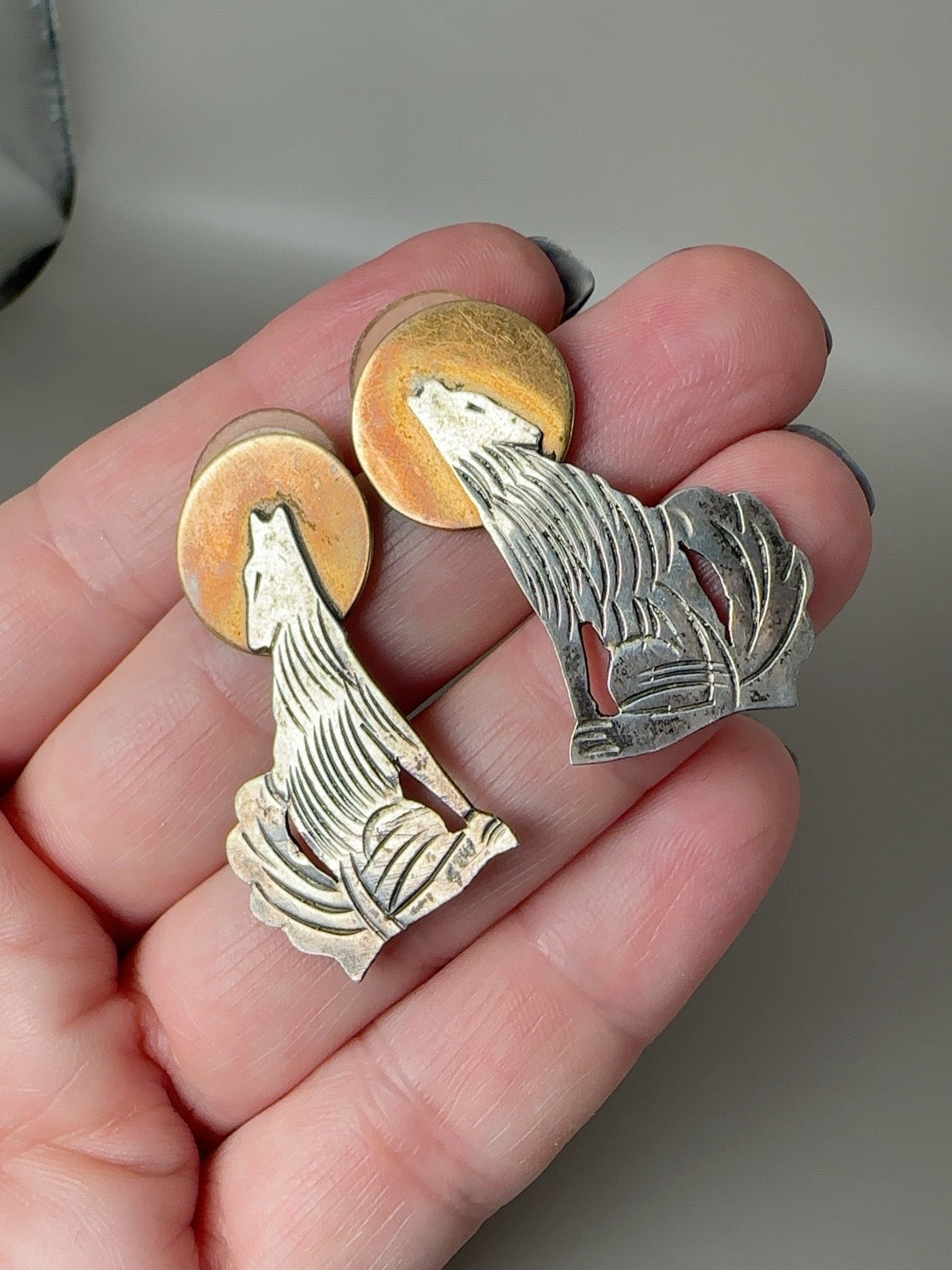 Vintage sterling silver and brass howling coyote moon earrings shown in hand for scale