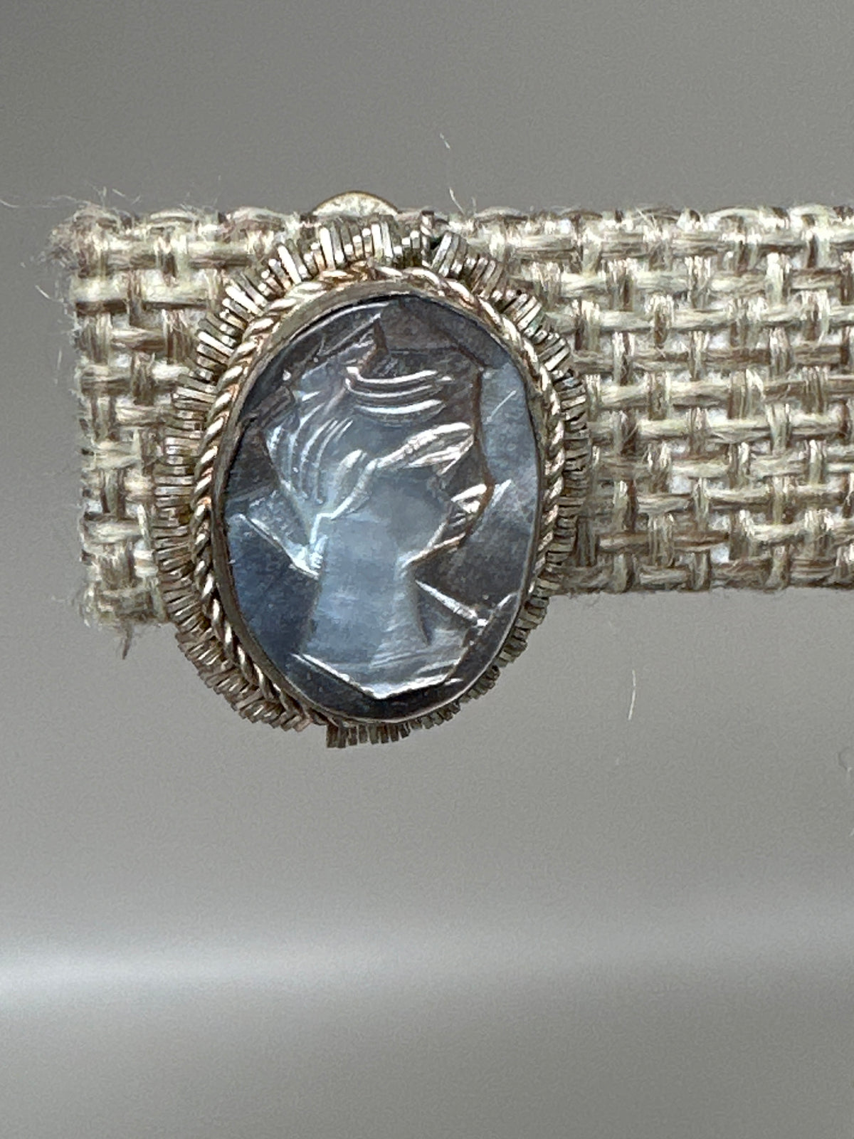 close-up of carved mother-of-pearl cameo showing left-facing female profile with detailed hair and features