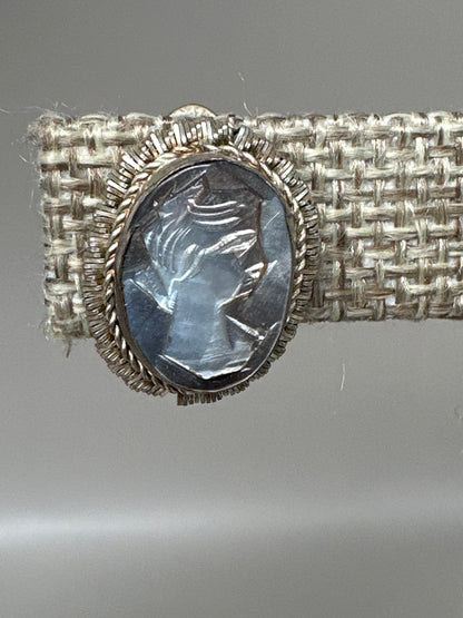 close-up of carved mother-of-pearl cameo showing left-facing female profile with detailed hair and features