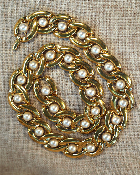 Gold-tone Napier chain necklace with faux pearl accents in each curb link, shown coiled on neutral linen