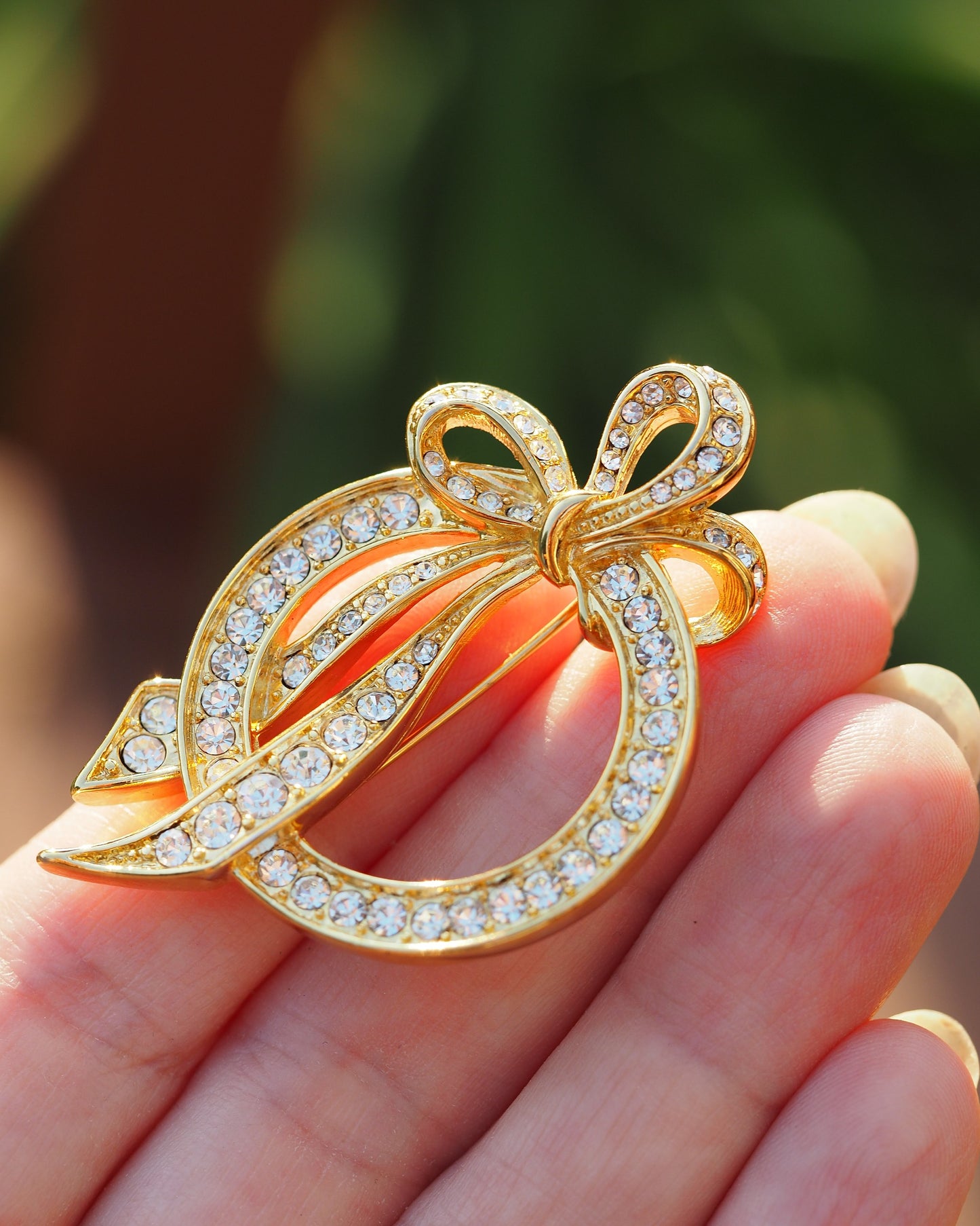 Nolan Miller rhinestone bow brooch held in hand for scale, showing 2-inch width against fingertips
