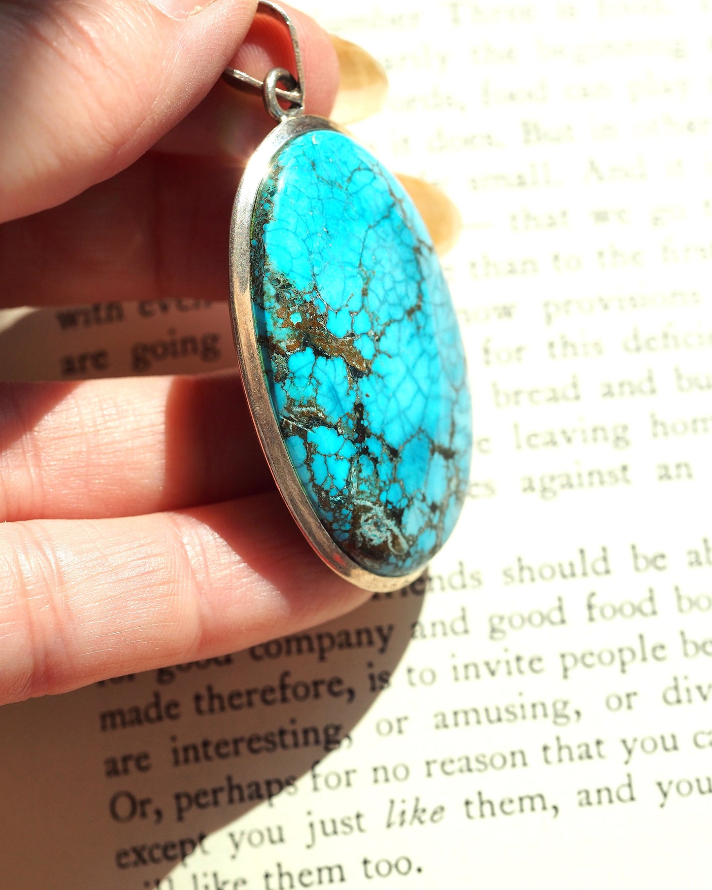 Sterling silver turquoise pendant held on fingertips for scale, showing 2 3/8 inch drop