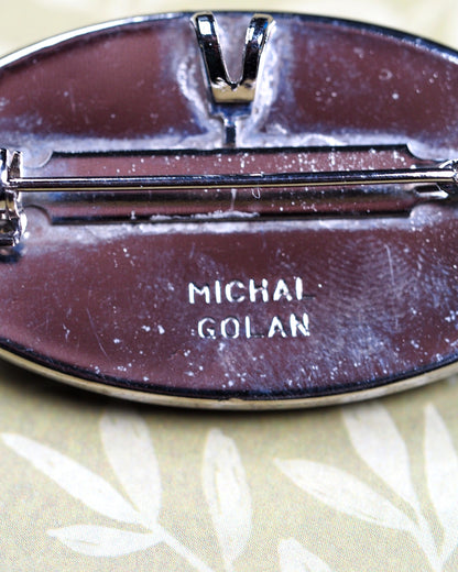 Close-up of Michal Golan signature on reverse of silver-tone oval brooch