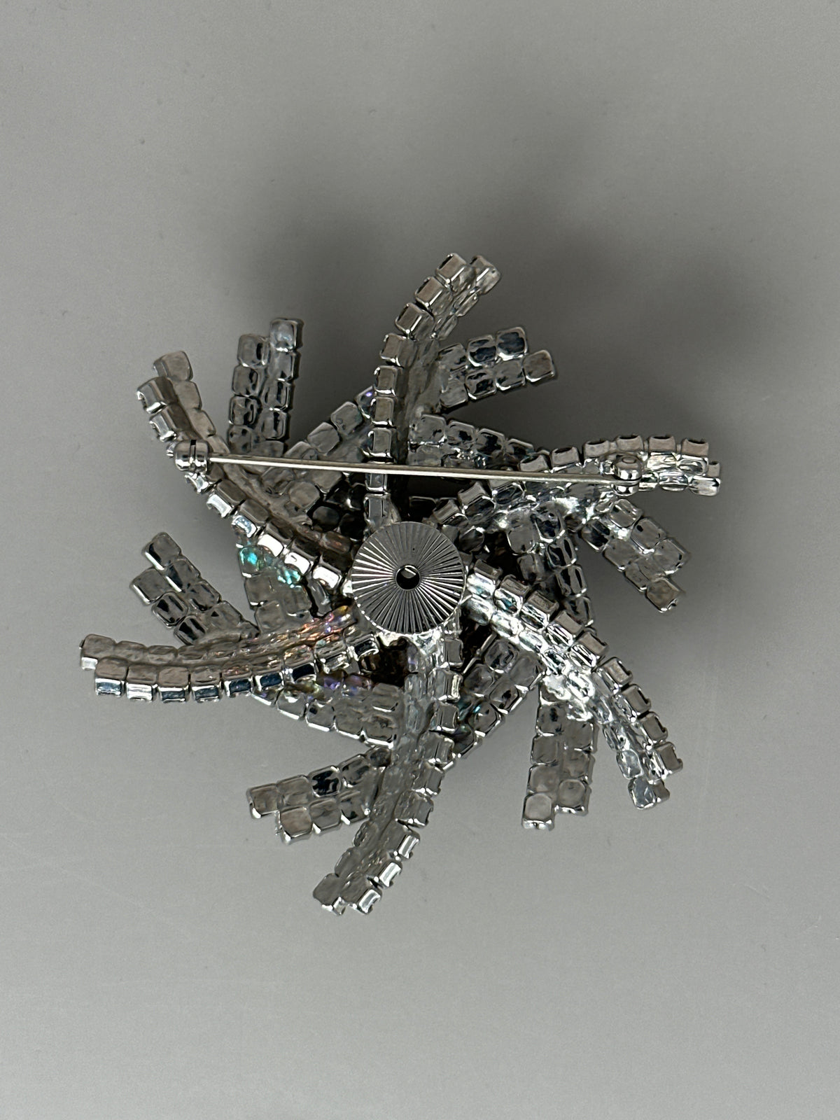Reverse of brooch showing trombone-style safety clasp with sunburst-engraved rotating head and prong construction