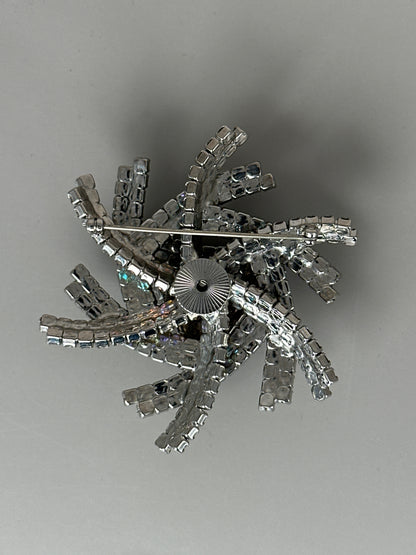 Reverse of brooch showing trombone-style safety clasp with sunburst-engraved rotating head and prong construction