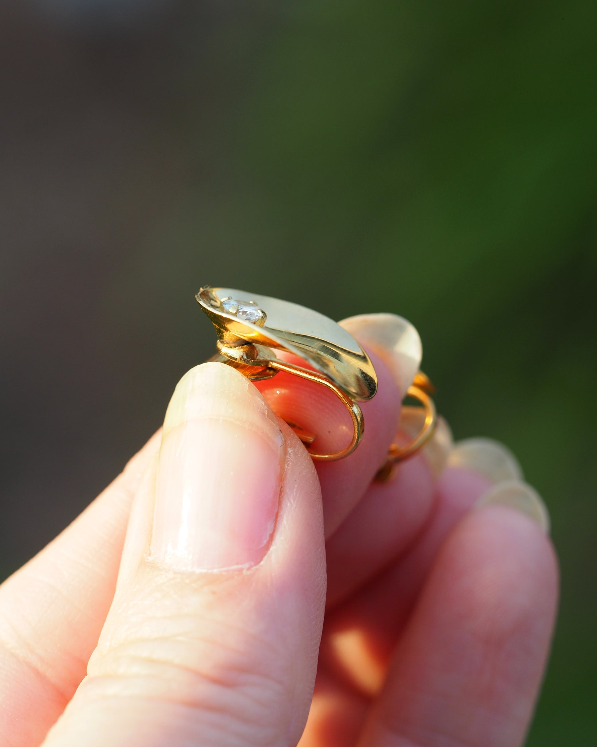 Side view of gold-tone clip earring showing clip-on mechanism and domed oval profile