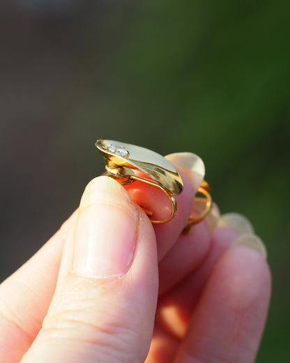 Side view of gold-tone clip earring showing clip-on mechanism and domed oval profile