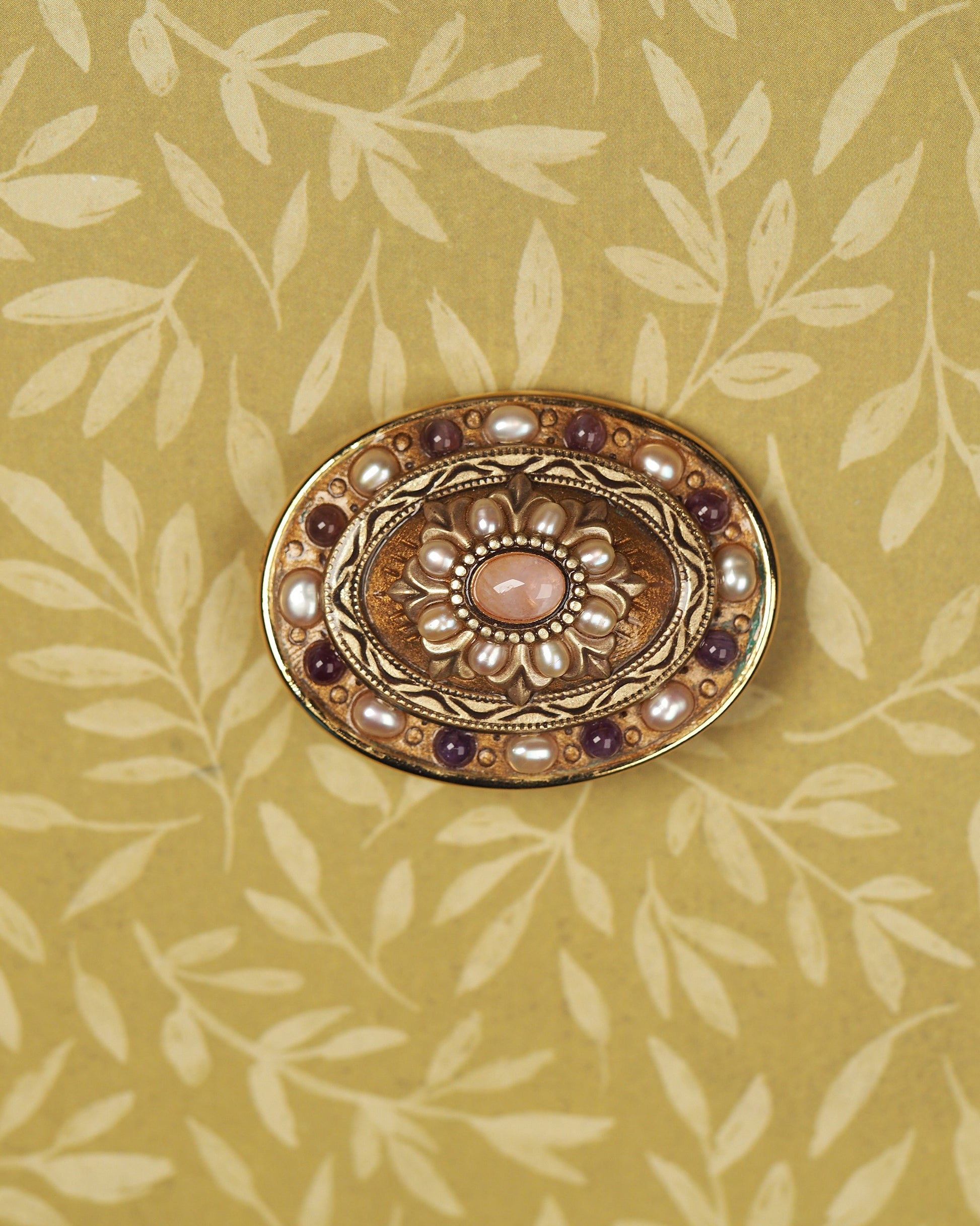 Signed Michal Golan gold-tone brooch with rose-colored quartz center, pearl-like petals, and purple accents, front view