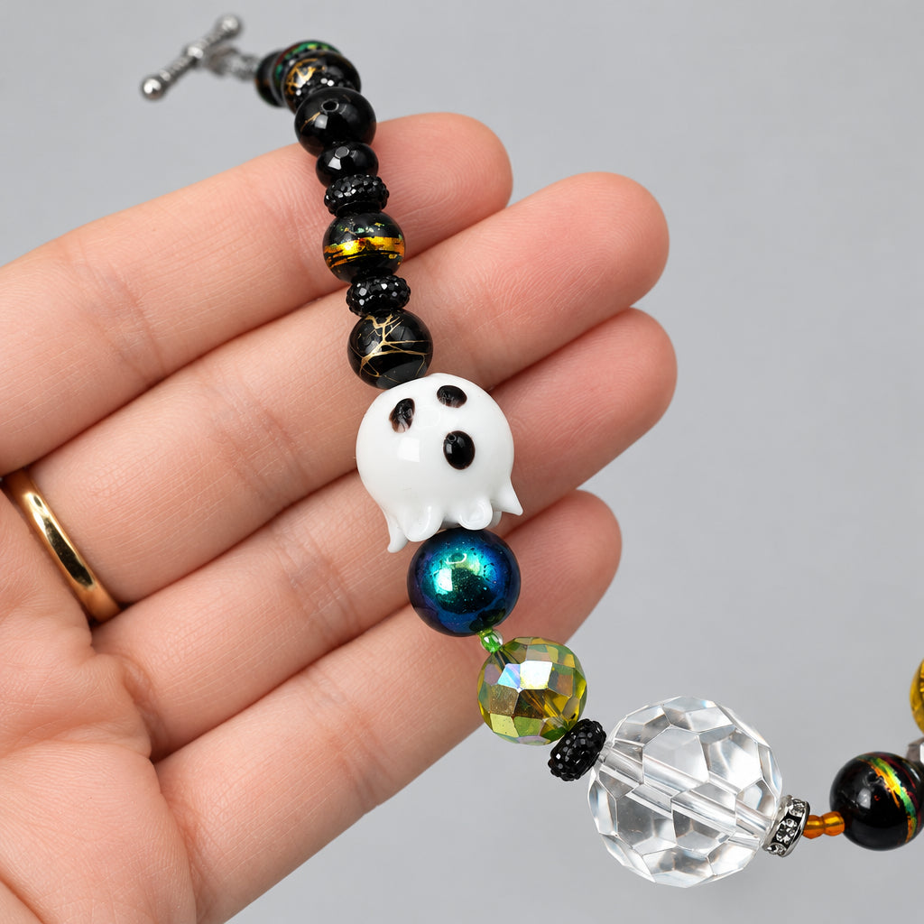 White glass ghost bead on Halloween necklace held in hand for scale