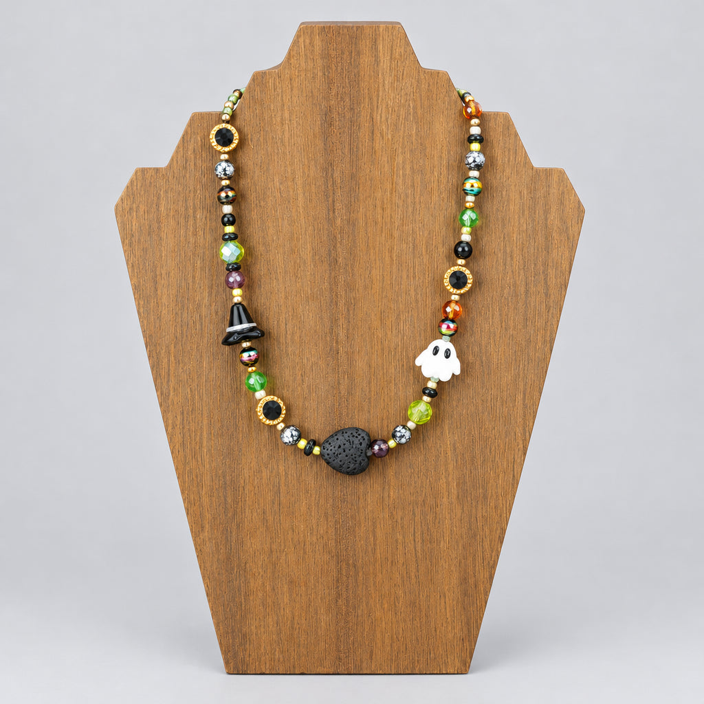 Handmade glass bead necklace with white ghost bead, black lava stone heart, and multicolor blown glass beads displayed on wood necklace stand, front view