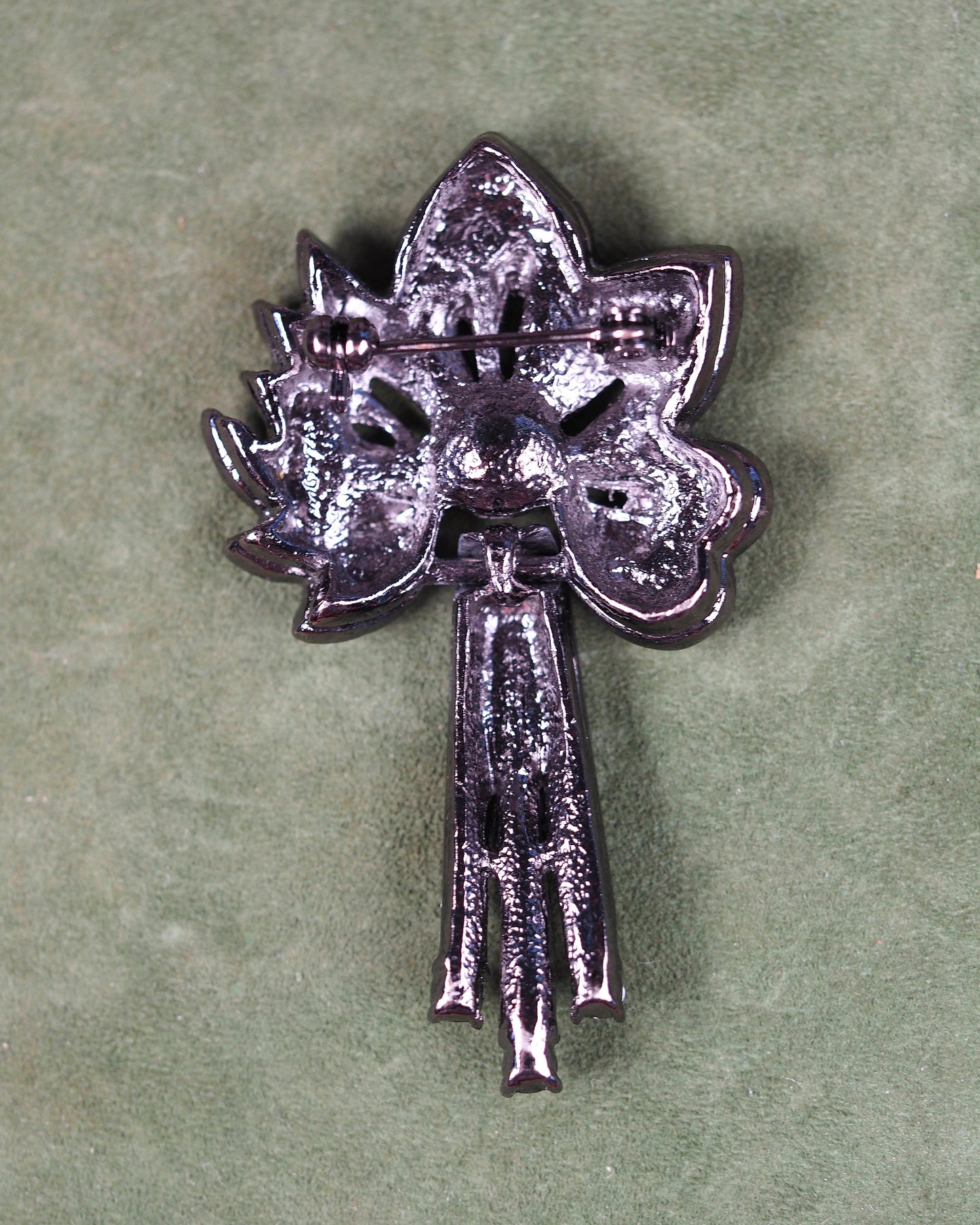 reverse side of teal rhinestone flower brooch showing gunmetal finish and horizontal pin mechanism