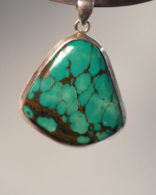 Sterling silver pendant with freeform turquoise-blue stone, bronze matrix webbing, front view