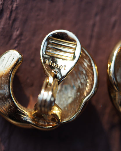 Close-up of Monet © signature stamp on the clip mechanism of the gold-plated earring