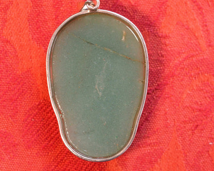 Back of aventurine skull pendant showing smooth polished stone reverse and sterling silver bezel, natural color variations visible