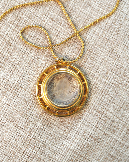 Back view of gold-tone openwork pendant frame with carved glass cameo center on twisted rope chain