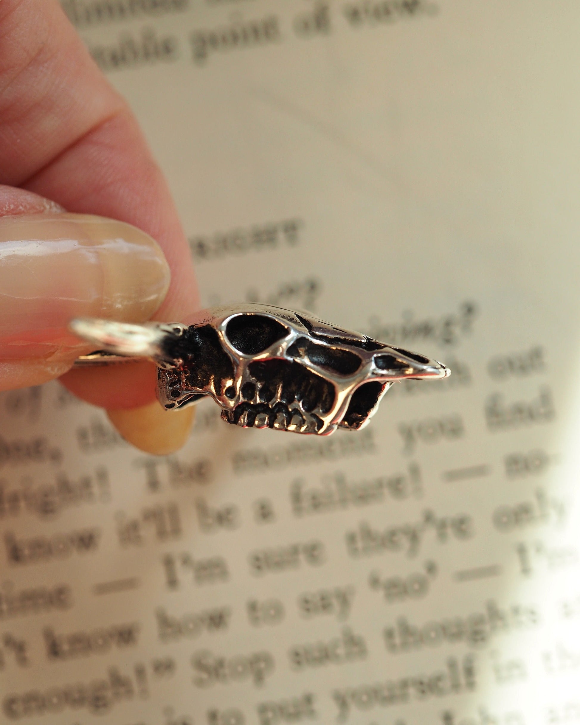 Sterling silver longhorn skull pendant held on fingertips for scale reference